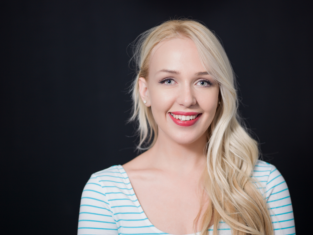 Vrouw toont haar beste haarkleur voor vuile blondines als gouden platina blond op een zwarte achtergrond