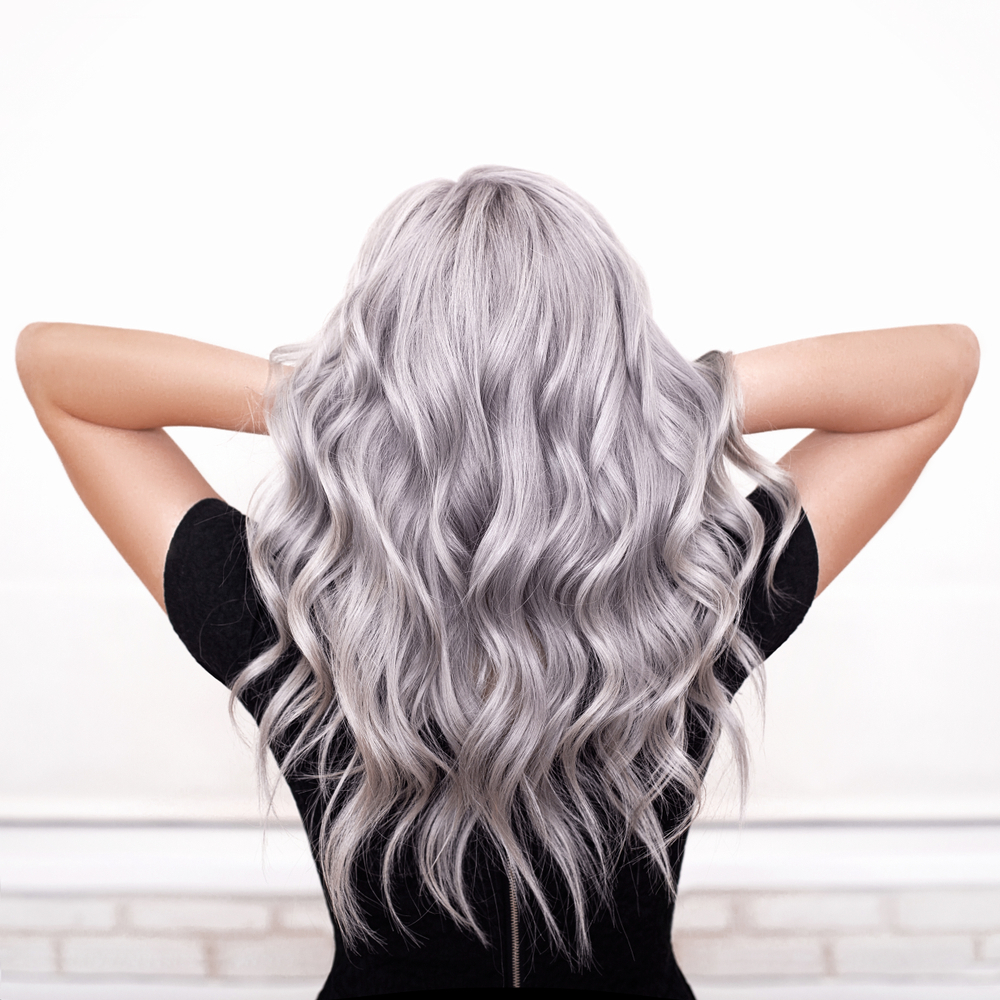 Achteraanzicht van vrouw met lang zilver golvend haar dat één van de beste haarkleuren voor vuile blondines toont