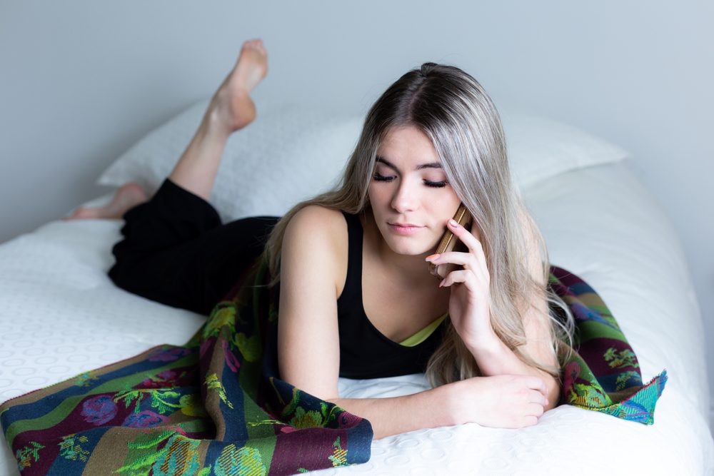 Ashy blonde haren vrouw getoond liggend op bed als een van de opties voor beste haarkleur voor vuile blondines