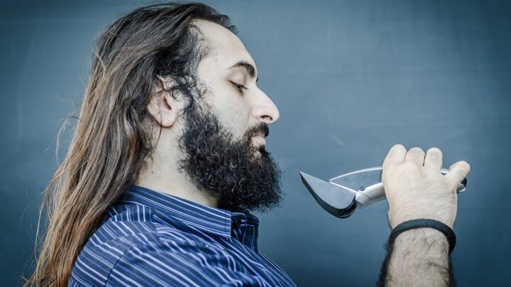 Man met lang haar en baard die een tondeuse vasthoudt