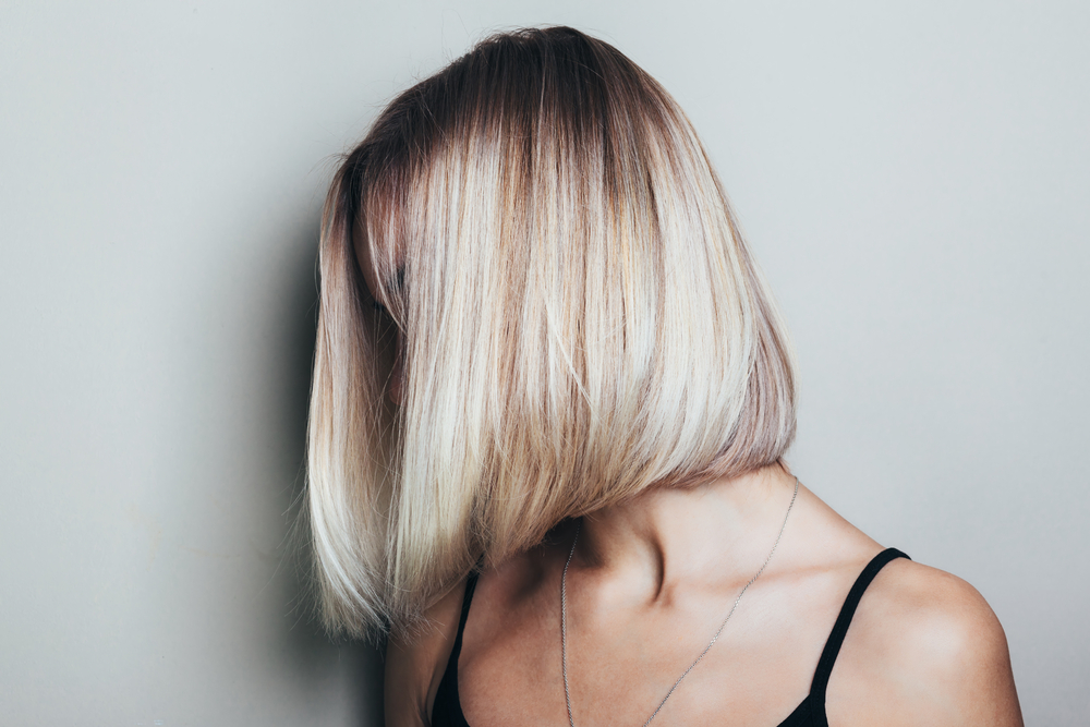 Model met onherkenbaar gezicht pronkt met neutrale blonde haarkleur voor kort haar