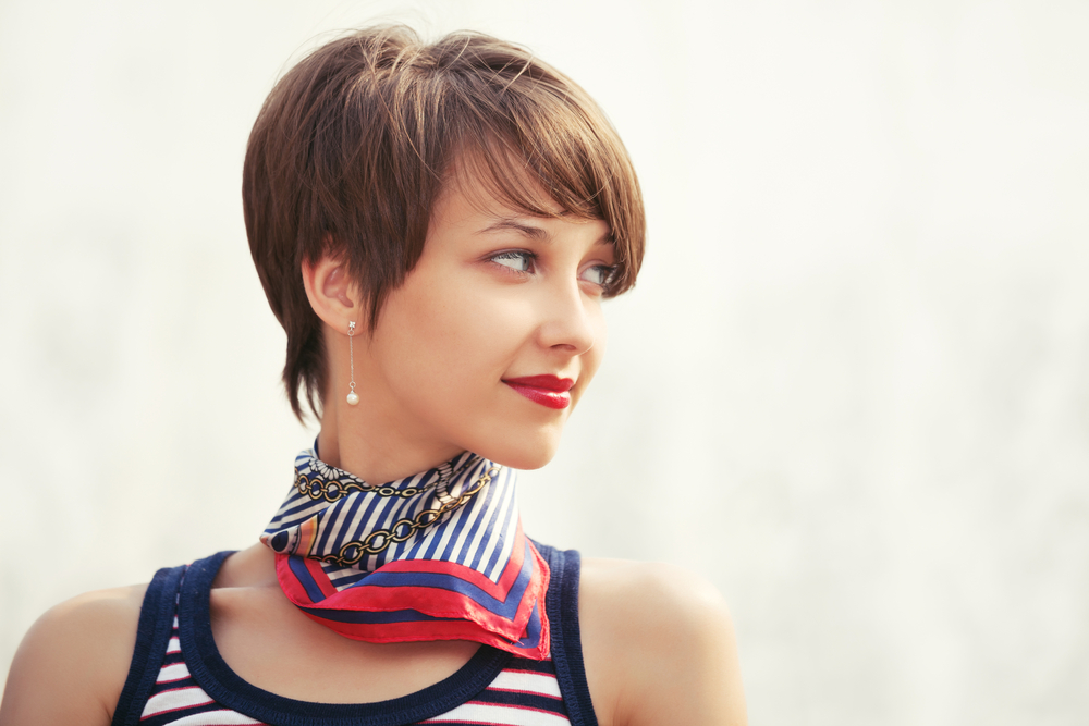 Vrouw kijkt opzij met gedessineerde sjaal en toont een van de beste haarkleuren voor kort haar