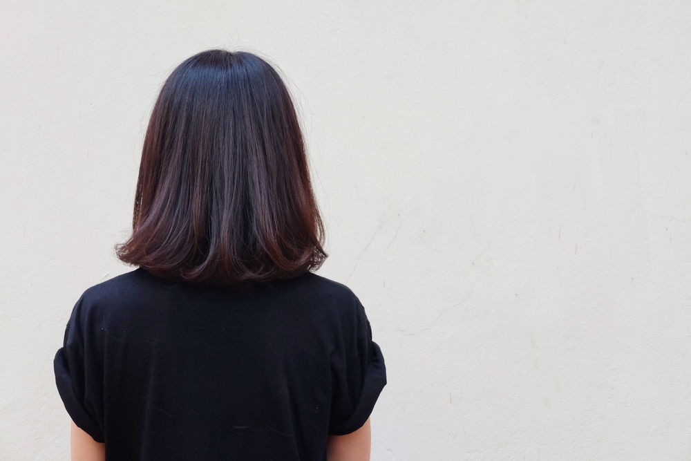 Vrouw van achteren gezien met zwart t-shirt modellen schouderlang donkerbruin haar met kastanjebruine balayage