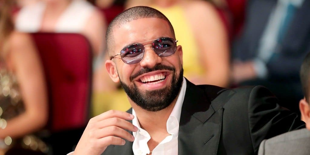 Drake Met Korte Baard en Bril Glimlachend