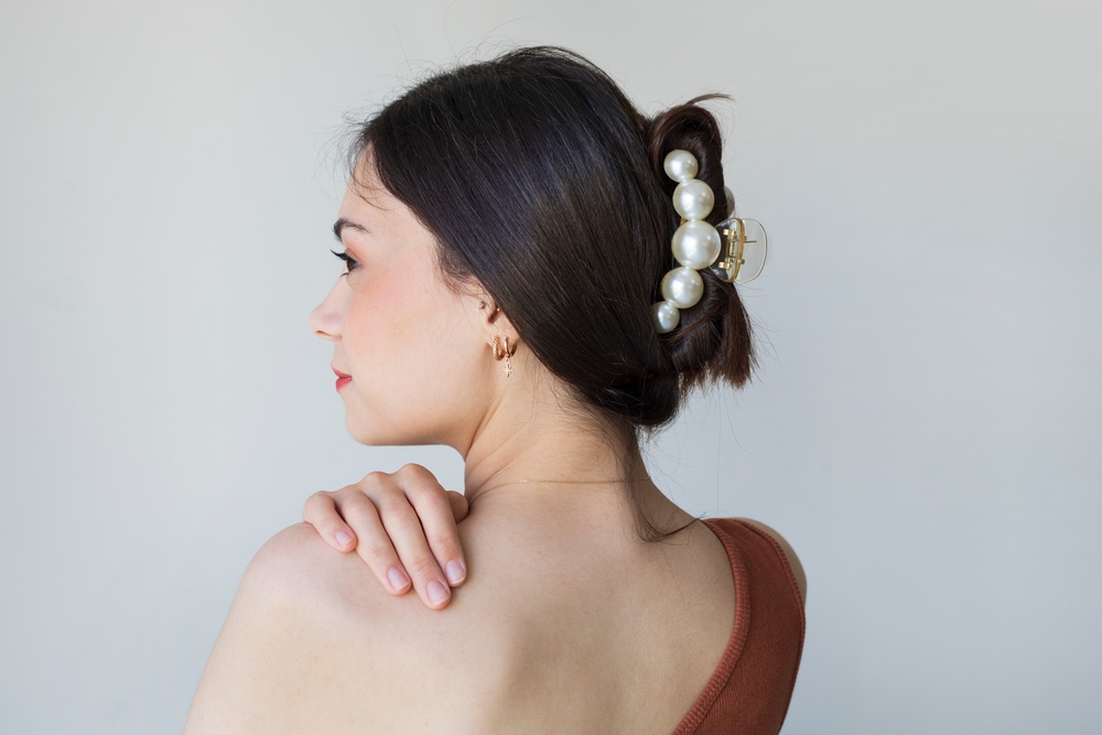 Brunette vrouw die een rode one-shoulder jurk draagt pronkt met één van de gemakkelijke kapsels voor lang dun haar met een snelle klauwclip updo.