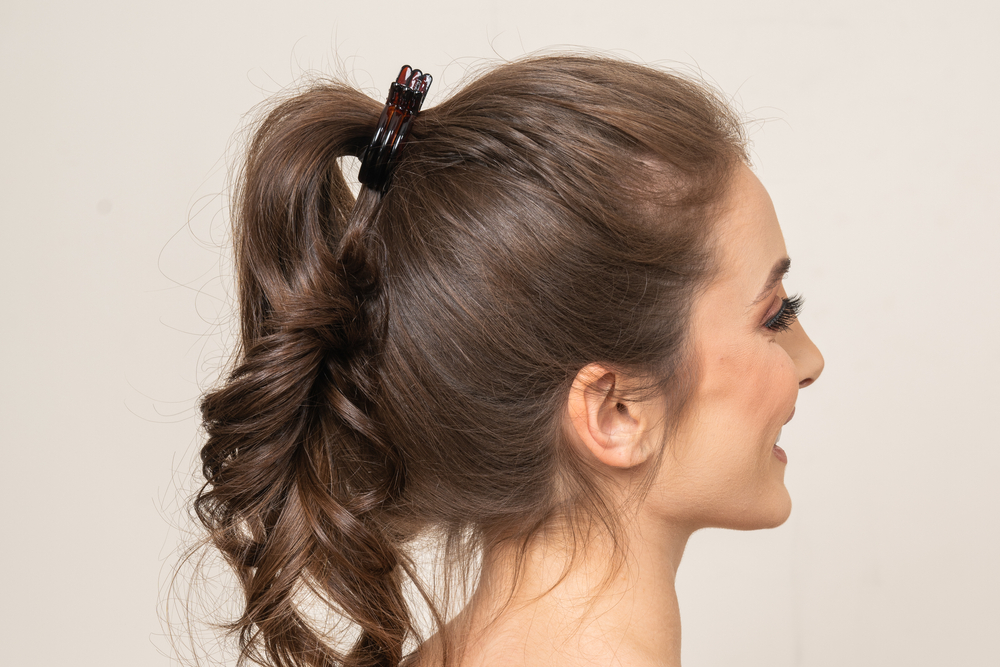 Achteraanzicht van een lachende vrouw met één van de topkapsels voor lang dun haar, een paardenstaart met extra volume achteraan