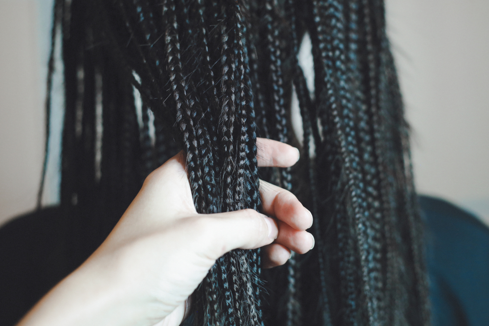 Vrouw pakt handvol kleine box braids om hun textuur van dichtbij te tonen