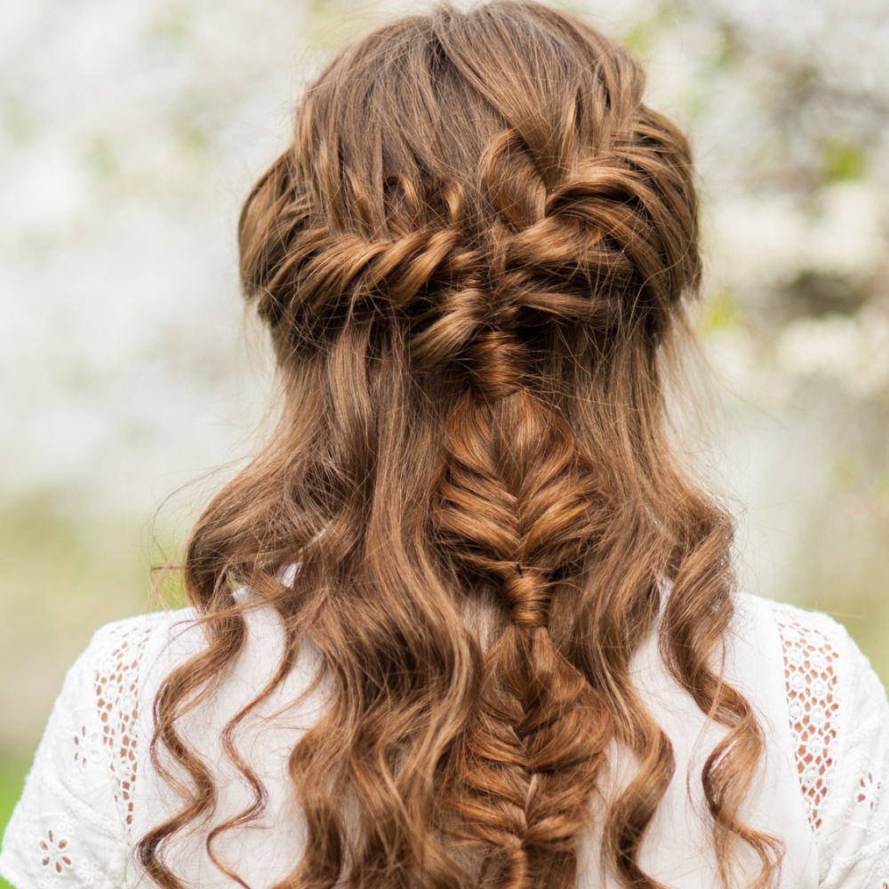 Achteraanzicht van vrouw met kastanjebruin haar die half op half neer gevlochten kapsel en witte gehaakte top draagt