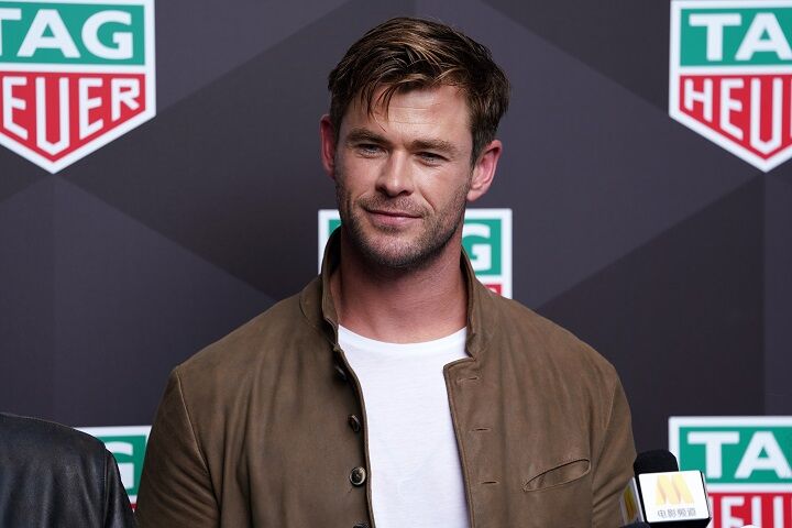 Glimlachende Chris Hemsworth in een jasje met een stoppelbaardje