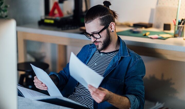 Man met bril en een man Bun kapsel kijken door middel van papieren