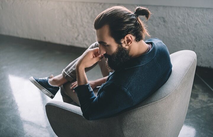 Man met een lange dikke baard en een kleine man bun zittend in een stoel