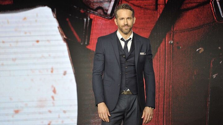 Ryan Reynolds in een zwart pak met een korte baard