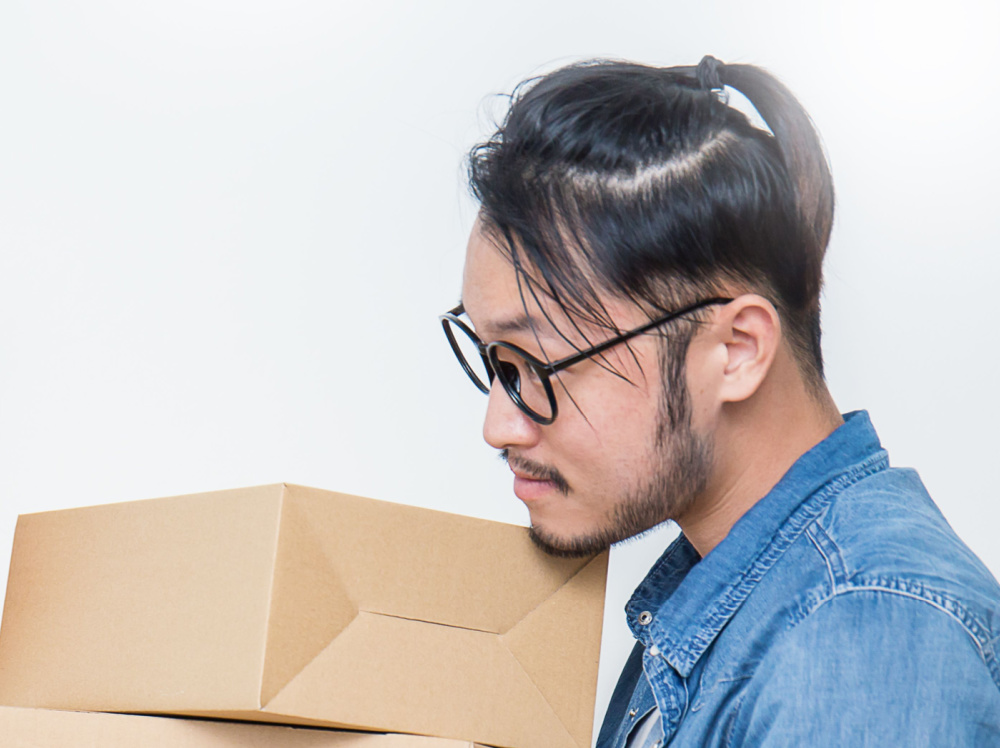 Man die dozen tilt draagt een denim shirt en half omhoog half omlaag man bun kapsel met lang haar