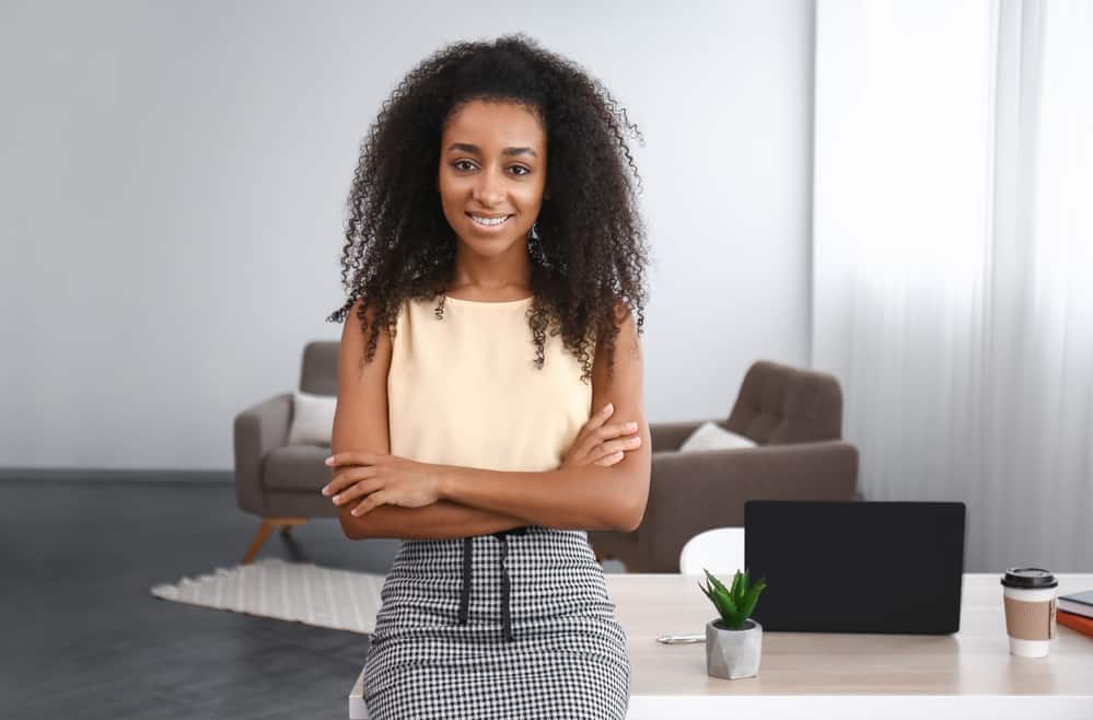 zwarte vrouwen die een geel overhemd en een houndstooth rok dragen.