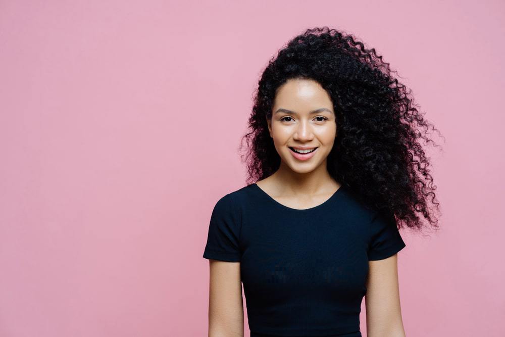 Licht gevilde Afro-Amerikaanse vrouw die een blauw t-shirt draagt met bergamotolie gehydrateerd haar. 