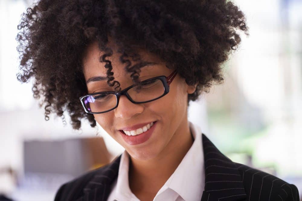 Succesvolle jonge Afro-Amerikaanse zakenvrouw die er gefocust uitziet terwijl ze aan een digitale tablet in haar huis werktffice.