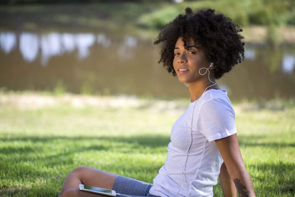 Portret van een jonge Afro-Amerikaanse vrouw die naar muziek luistert op mobiele telefoon