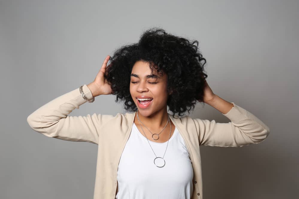 Mooie Afro-Amerikaanse vrouw met krullend haar met haar ogen dicht.