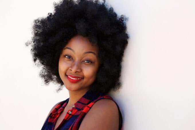 Mooie Afro-Amerikaanse vrouwen met 4C haartype die een rood en blauw flanellen shirt dragen.