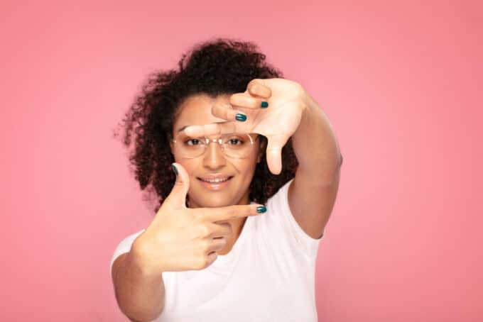 Afro-Amerikaanse vrouw met een wit t-shirt, groene nagellak en krullend haar. 