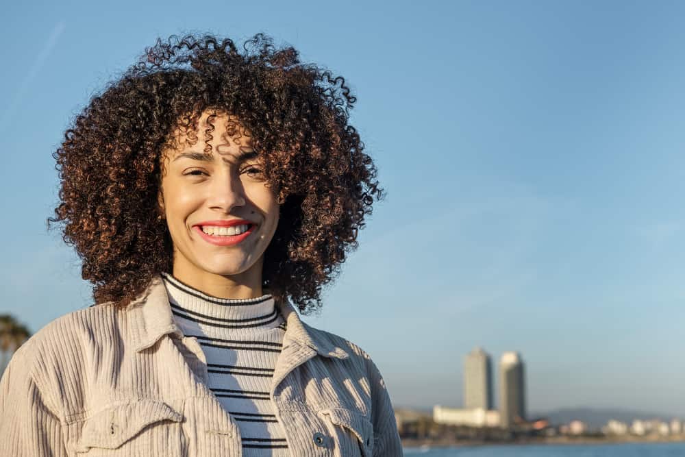 Mooie Afro-Amerikaanse vrouw met natuurlijk haar die voor een skyline van New York City staat.