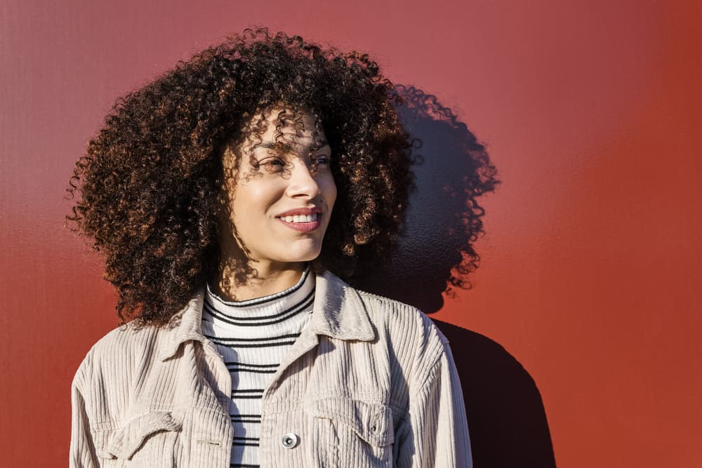 Afro-Amerikaanse vrouw met een grote glimlach rocken een type 3a krullend afro kapsel.