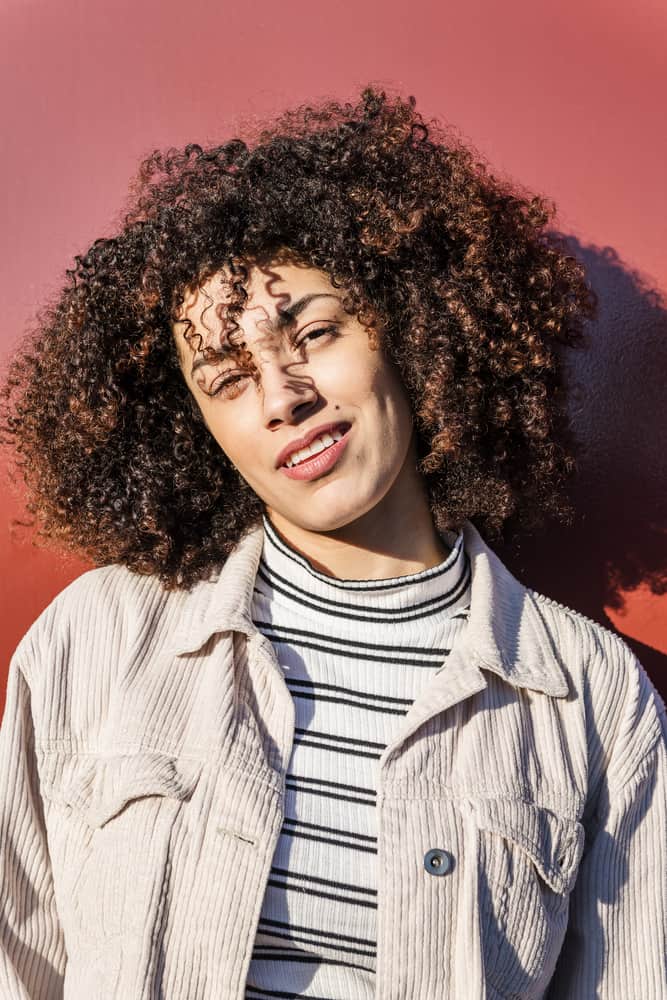 Latina vrouwen met een type 3 krullend kapsel dragen een corduroy jasje, wit en zwart gestreept ondershirt en roze lippenstift.