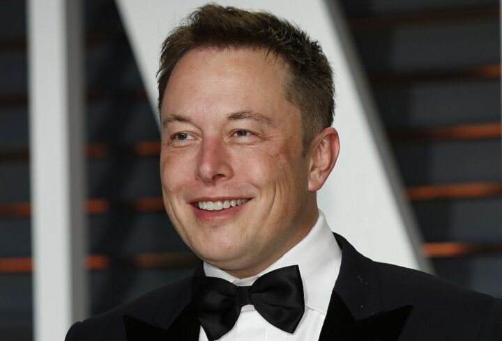 Glimlachende Elon Musk in een pak met stropdas
