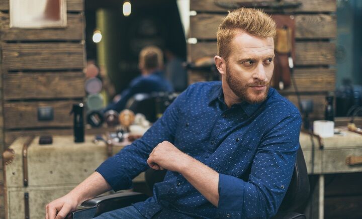 Bebaarde man met rood geknipt haar in een blauw shirt