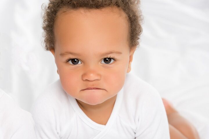 Baby jongen met krullend haar en gek gezicht