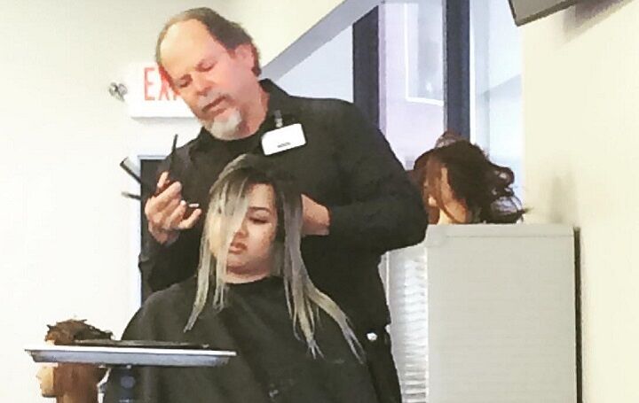 Stylist die het haar van een vrouw verft in de Paul Mitchell kapsalon