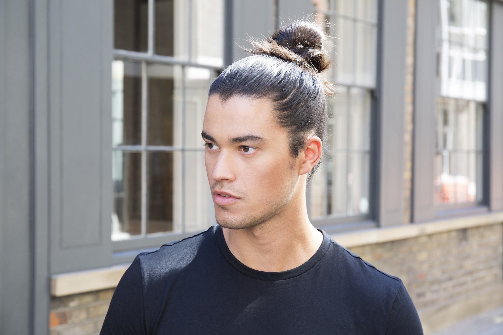 Man bun tutorial brunette man die wegkijkt van de camera die op straat staat