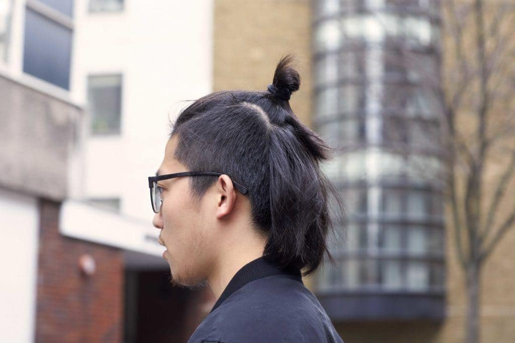 undercut man bun van een Aziatische man die in de stad loopt