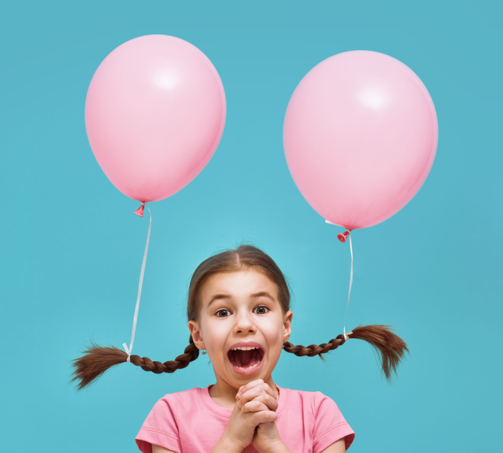 Klein meisje in roze t-shirt draagt vlechten met roze ballonnen in bijlage voor een stuk op gekke haardag ideeën 