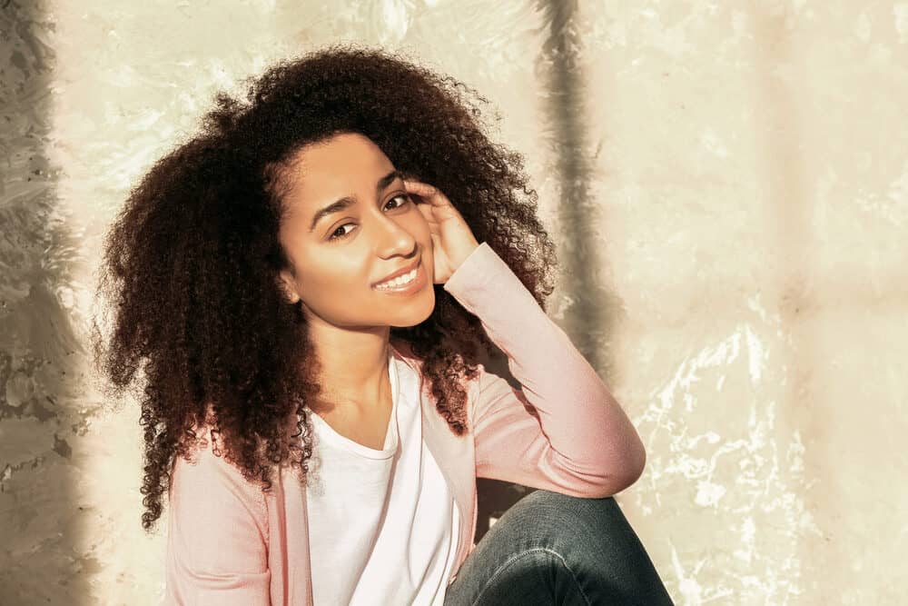 Mooie Afro-Amerikaanse vrouw die op de grond zit in de buurt van een grungemuur.