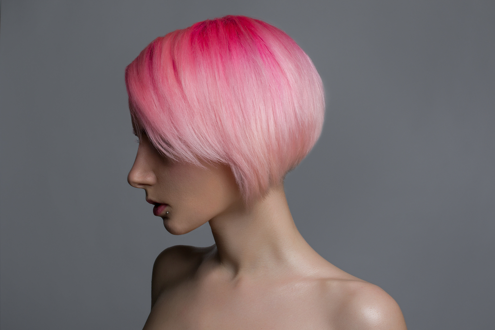 Blond en roze haarkleur op een vrouw met blanke huid in een grijze kamer