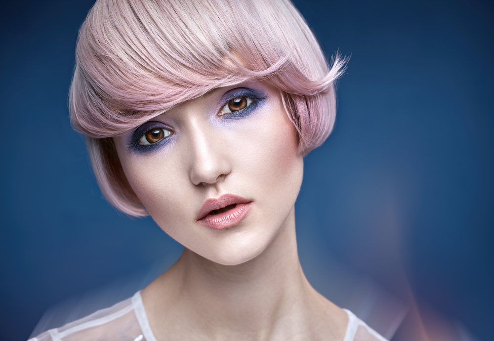 Barely-There Silk Pink haar als kenmerkend lichtroze kapsel met lichtroze lippenstift in een blauwe kamer
