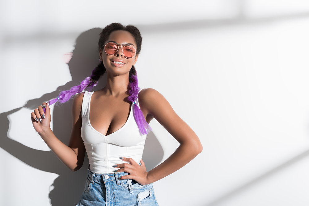 Afro-Amerikaans meisje met witte tank en denim shorts draagt haar haar in Franse vlechten en lavendel ombre kleur