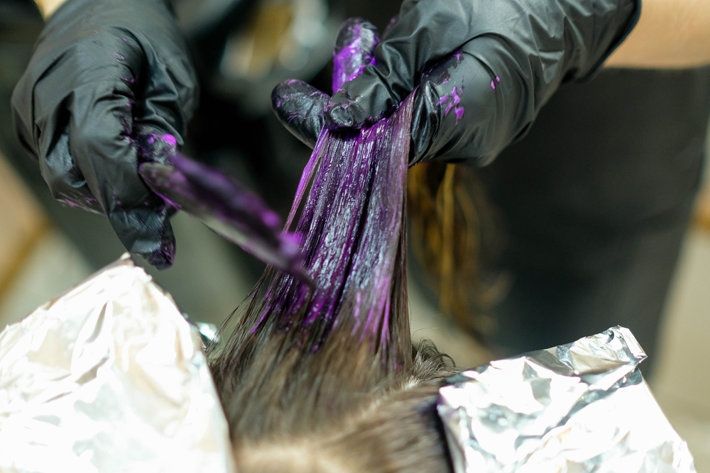 Close up van stylist die bruin haar kleurt met lavendel haarverf met behulp van een kleurborstel