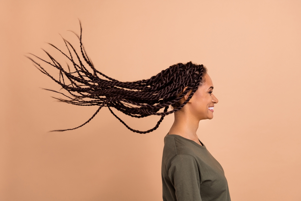 Gemengde vrouw zijaanzicht met opgestoken spring twist haar om de textuur te tonen voor perzikkleurige muur