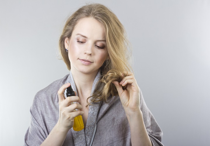 Vrouw die haar haar spuit met een haaroplossing