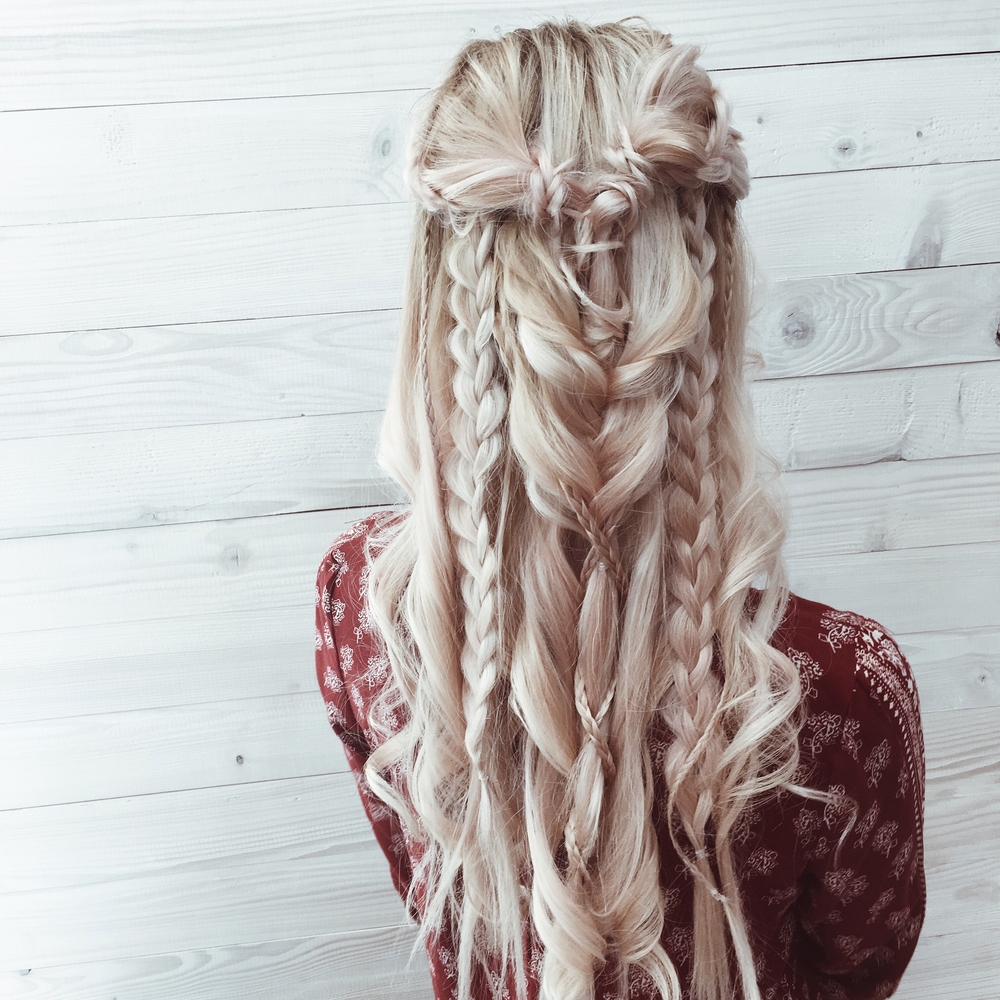 Blonde jonge vrouw draagt boho vlechten als een half up prom hairstyle met zachte golven