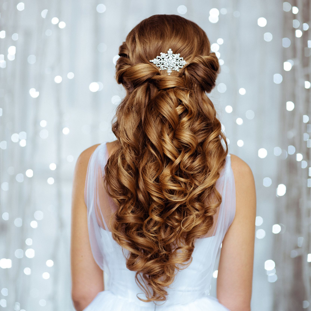 Meisje met koperrood haar draagt een van de beste half up prom kapsels met twists en krullen naast een witte jurk