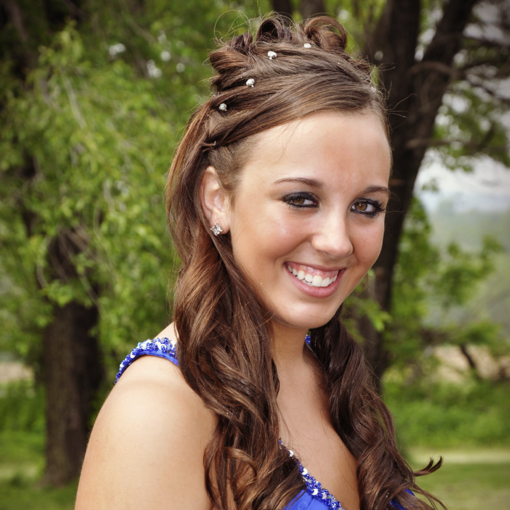 Bruinharig tienermeisje in blauwe jurk draagt een van de trendy half up prom kapsels met spelden en krullen