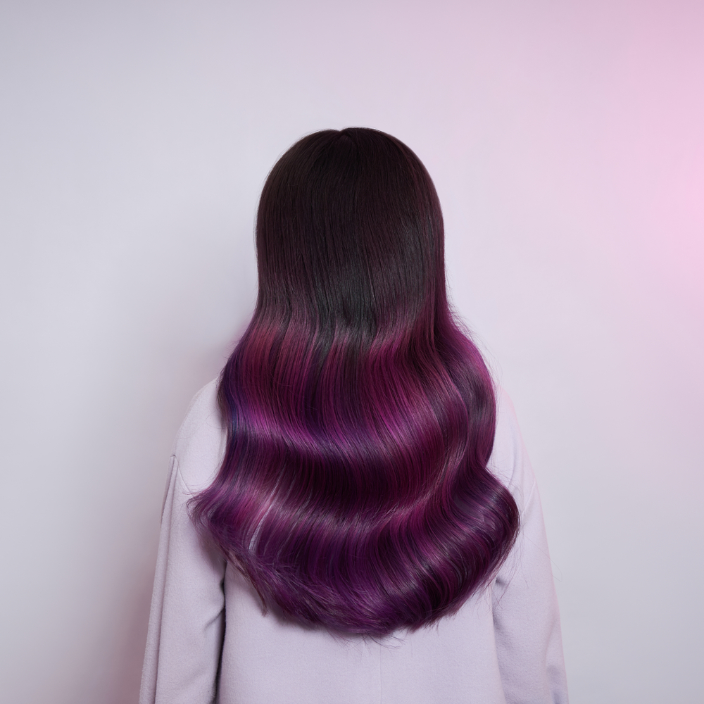 Achteraanzicht van plum balayage haarkleur met magenta tinten voor pastel muur