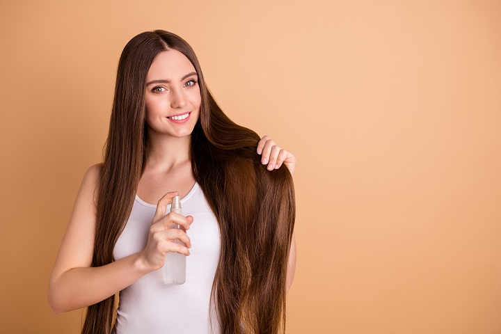 Meisje met een zeer lang haar serum aanbrengen