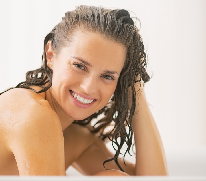 Glimlachende vrouw die haar haar wast
