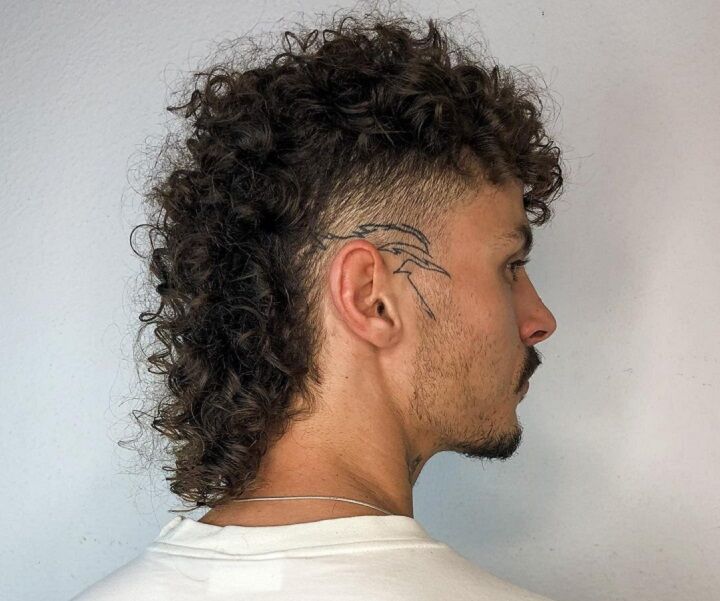 Man met een krullend mulkapsel en een tatoeage achter het oor